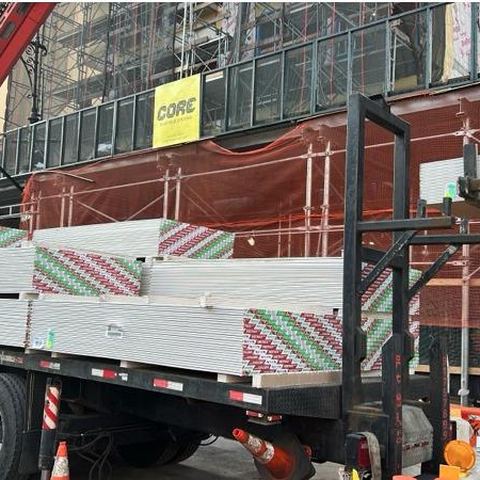Boom unloading sheetrock at a curbside delivery