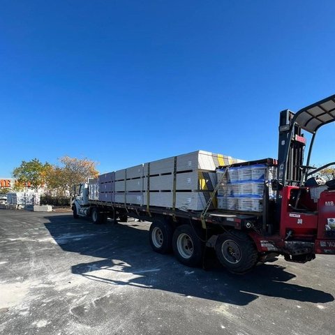 Boom truck with truck-mounted forklift in a supplier yard